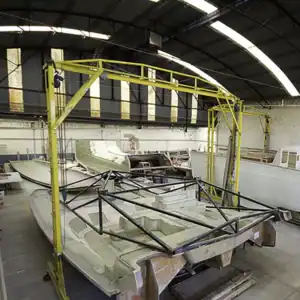 Lightweight catamaran boat under construction in a factory, ready for sailing or cruising adventures.