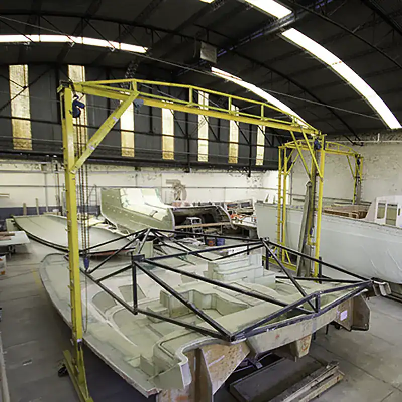 Lightweight catamaran boat under construction in a factory, ready for sailing or cruising adventures.