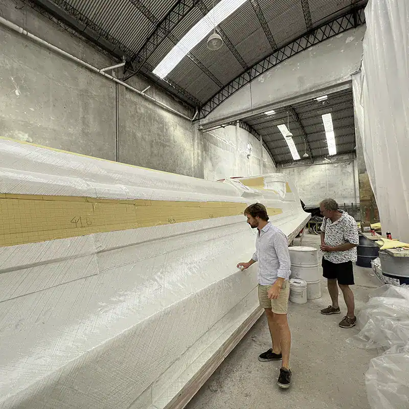 Custom-designed Antares catamaran being constructed in a large indoor manufacturing facility, showcasing the innovative build process and craftsmanship of high-performance cruising catamarans.