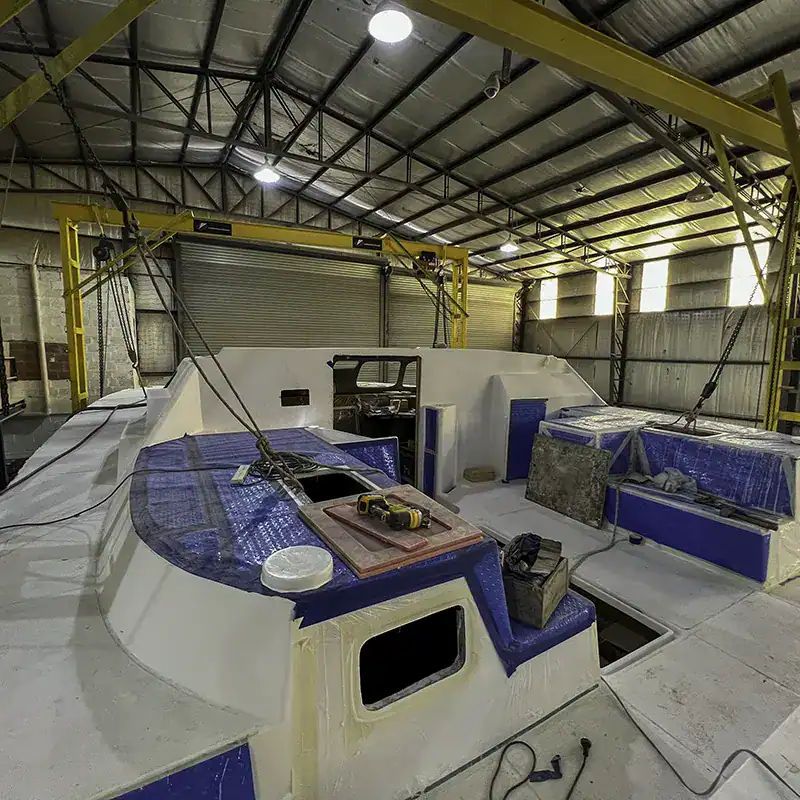 Motor yacht under construction at Antares Catamarans manufacturing facility, showcasing advanced fiberglass hull assembly and high-quality craftsmanship in a spacious industrial workshop.