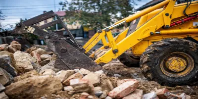 The yellow excavator expertly navigates the construction site, efficiently moving rubble and bricks as part of top-notch excavation services.