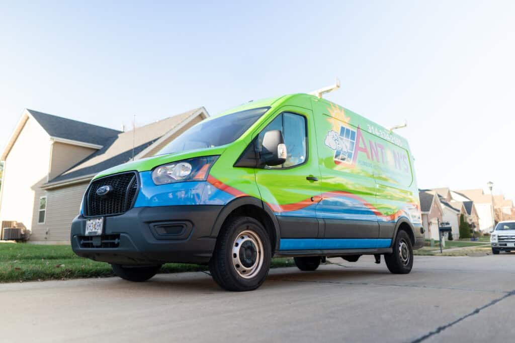 A colorful van parked on a residential street showcases a vibrant green and blue design with "Martinez Painting" text and logo on the side, reminding residents that just as paint upkeep is vital, so too is essential HVAC maintenance for cozy winter homes. Houses and a clear sky form the backdrop.