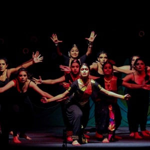 Group of dancers performing a traditional routine on stage with expressive hand gestures.