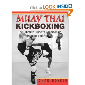 Muay Thai kickboxing training with a fighter executing a high kick.