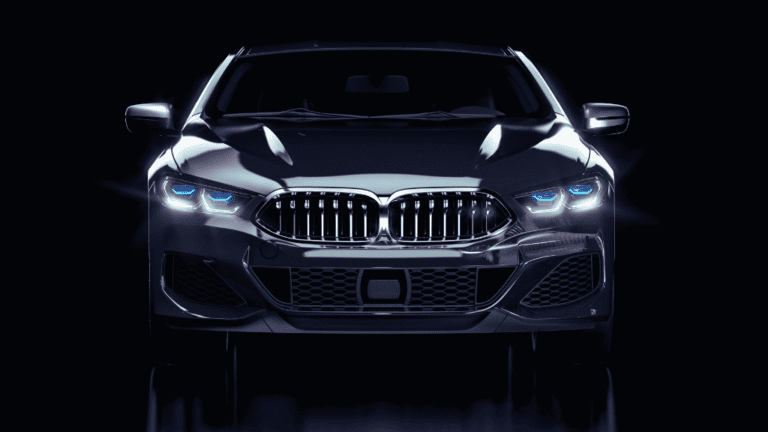 Une élégante voiture de luxe de couleur sombre est photographiée de face sur fond noir. Ses phares à DEL et sa calandre double emblématique brillent, affichant un design parfaitement adapté aux routes québécoises – idéal pour les clients exigeants en quête de véhicules haut de gamme.