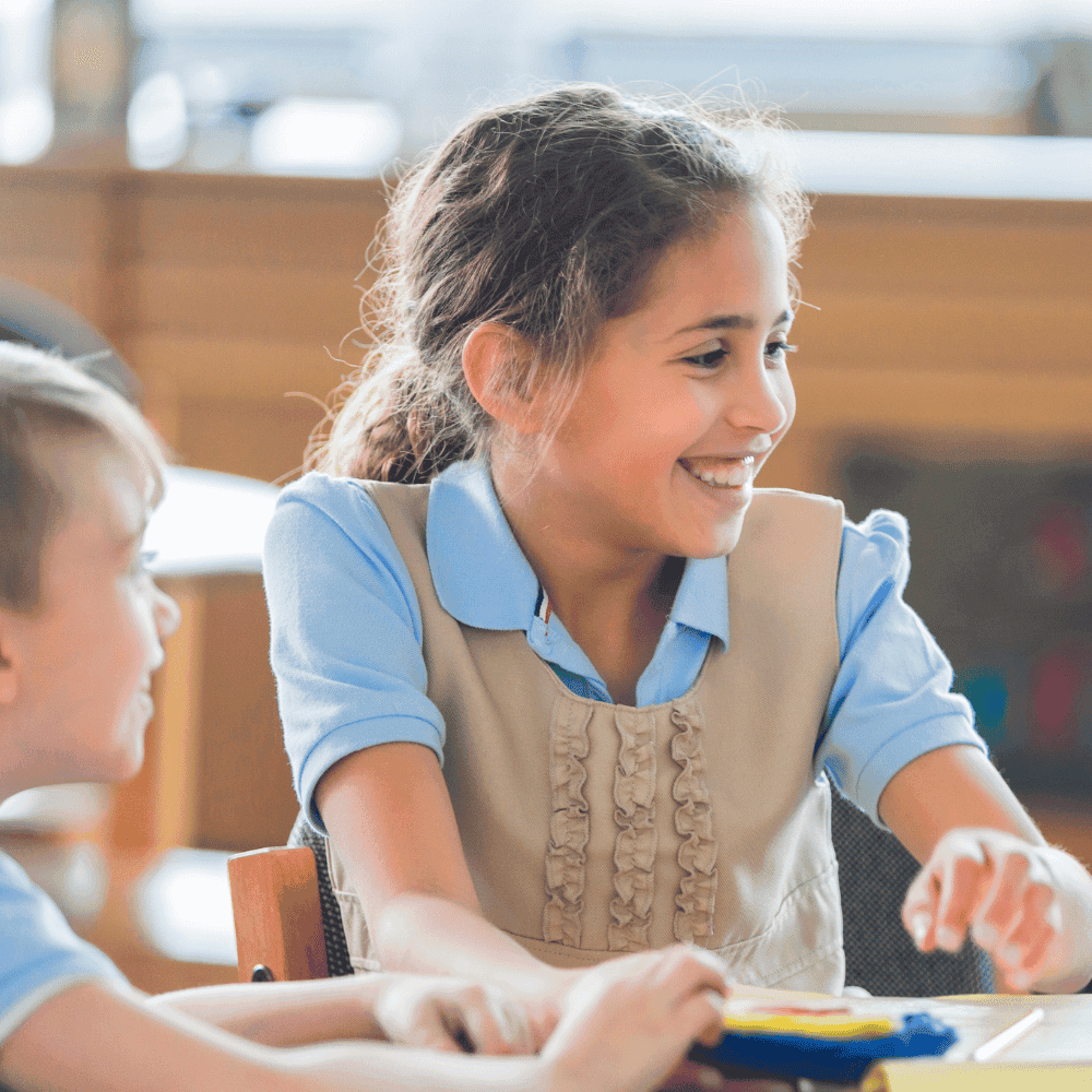 Enfants souriant en classe, portant uniforme scolaire.