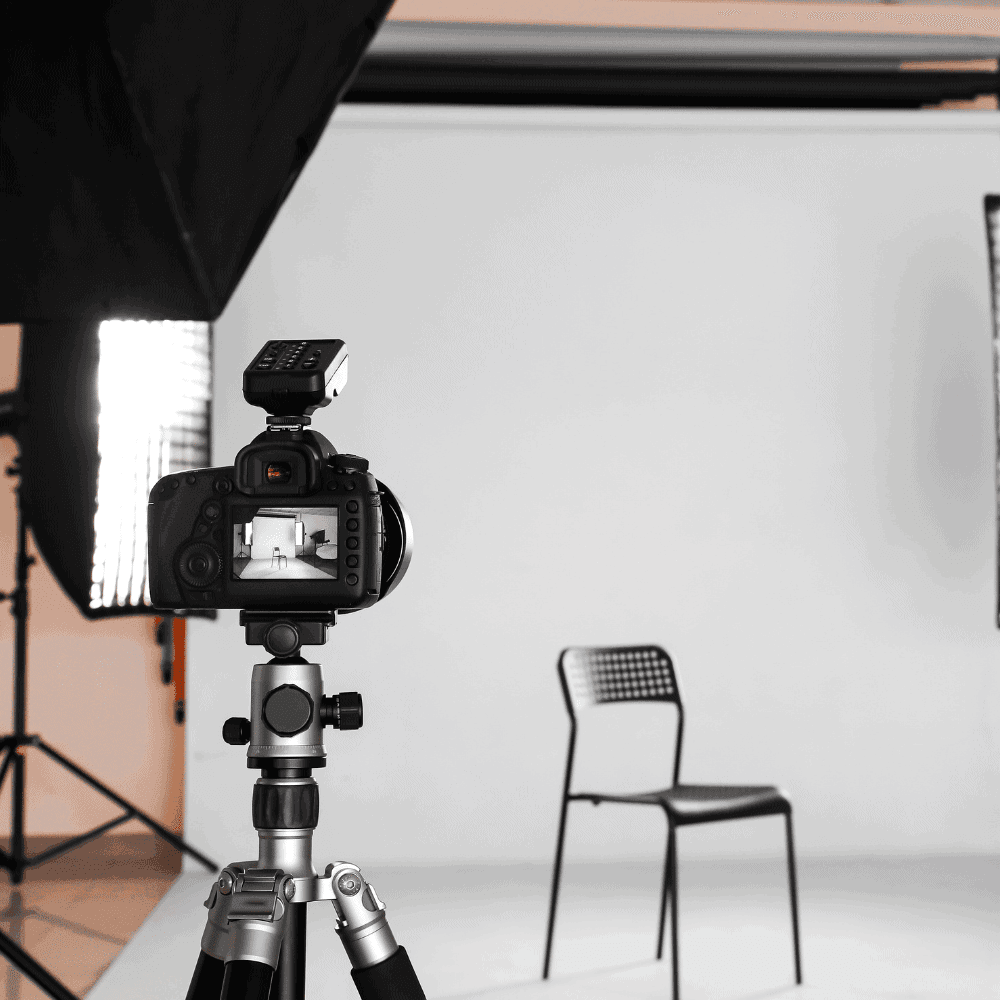 Photo studio avec caméra sur trépied, chaise vide.
