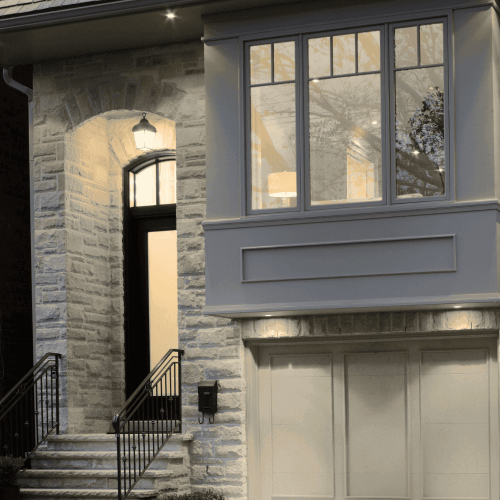 Façade de maison moderne en pierre grise éclairée.