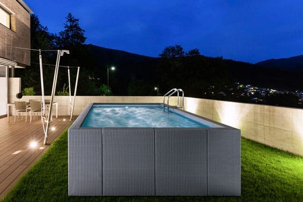 Piscina in pannelli di rattan grigi in un giardino di notte