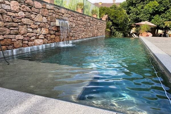 piscina con piastrelle grigie ed una cascata integrata al muro