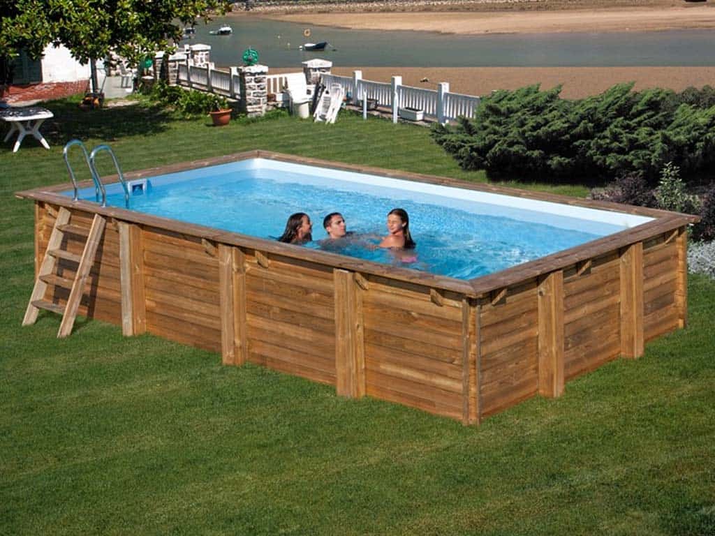 Piscina rettangolare fuori terra in legno con scala esterna in giardino.