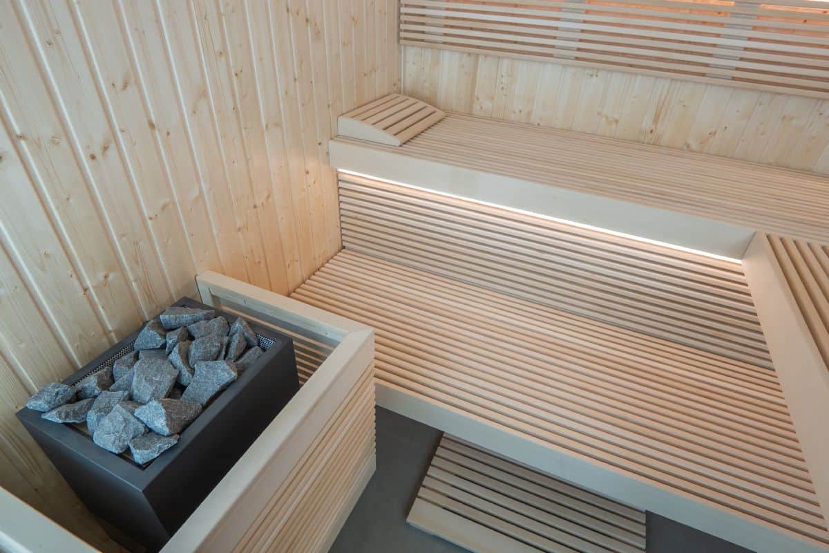 Sentiotec_Panorama Large_PANORAMA-L_d2 Panca sauna in legno con stufa a pietre, ambiente interno caldo e accogliente.