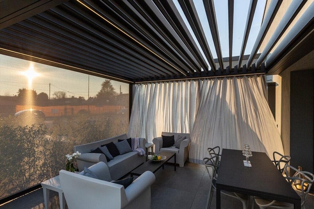 Relaxing outdoor wellness area with a covered lounge space, featuring comfortable seating and privacy curtains, ideal for relaxation after swimming in a private indoor pool.