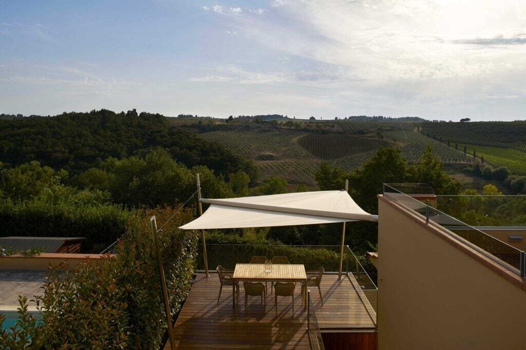 Veranda con tenda parasole e vista sui vigneti collinari, ambiente ideale per relax e socializzazione.