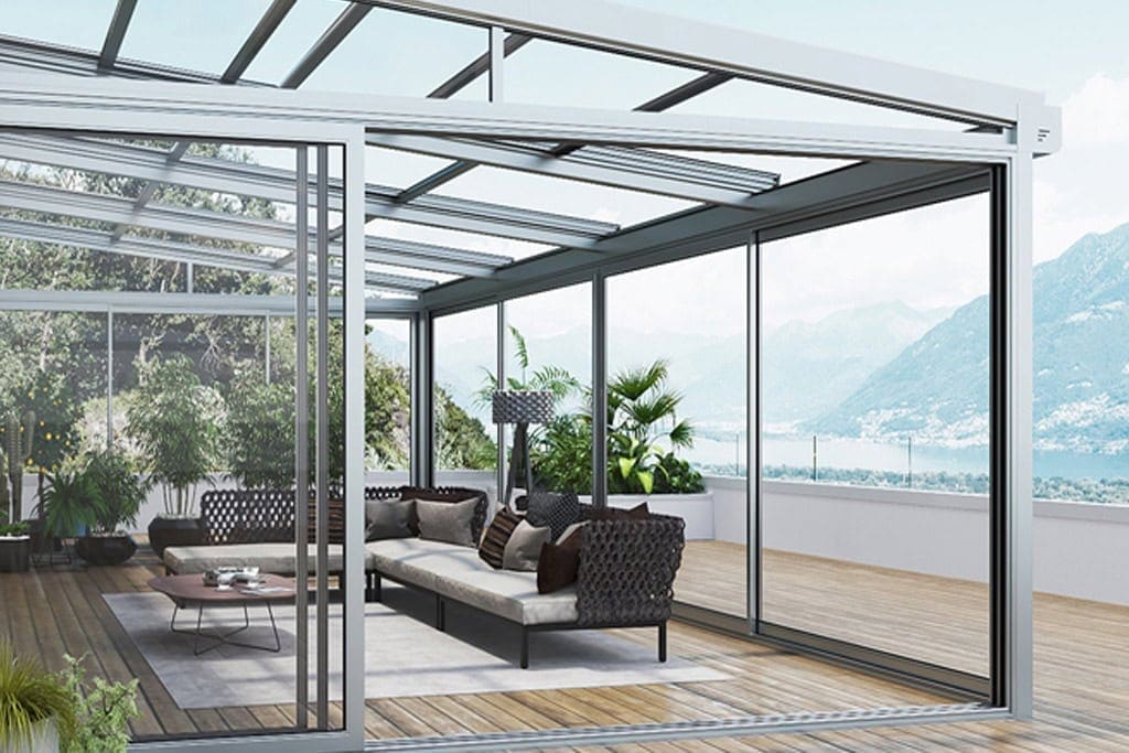 Elegante spazio lounge con pareti in vetro e tetto action, ideale come zona relax coperta con vista panoramica sulle montagne. Perfetto per ambienti outdoor di lusso e benessere.