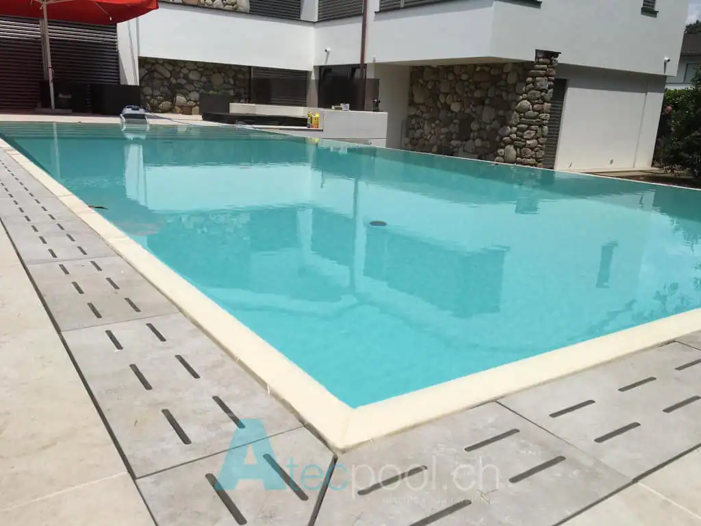 Piscina interrata con bordo a sfioro, acqua cristallina e design moderno, ideale per il relax e il benessere.