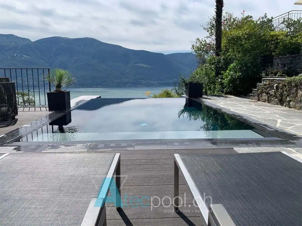 Piscina interrata infinity con vista lago e monti sullo sfondo.