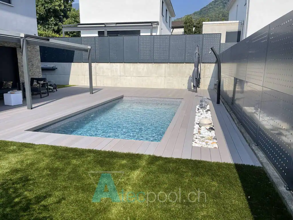 Piscina interrata con struttura moderna e superficie in legno, zona wellness esterna raffinata e semplice.