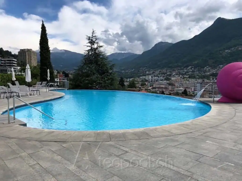 Piscina interrata a sfioro con vista sulle montagne e la città, piscina per il relax e il benessere.