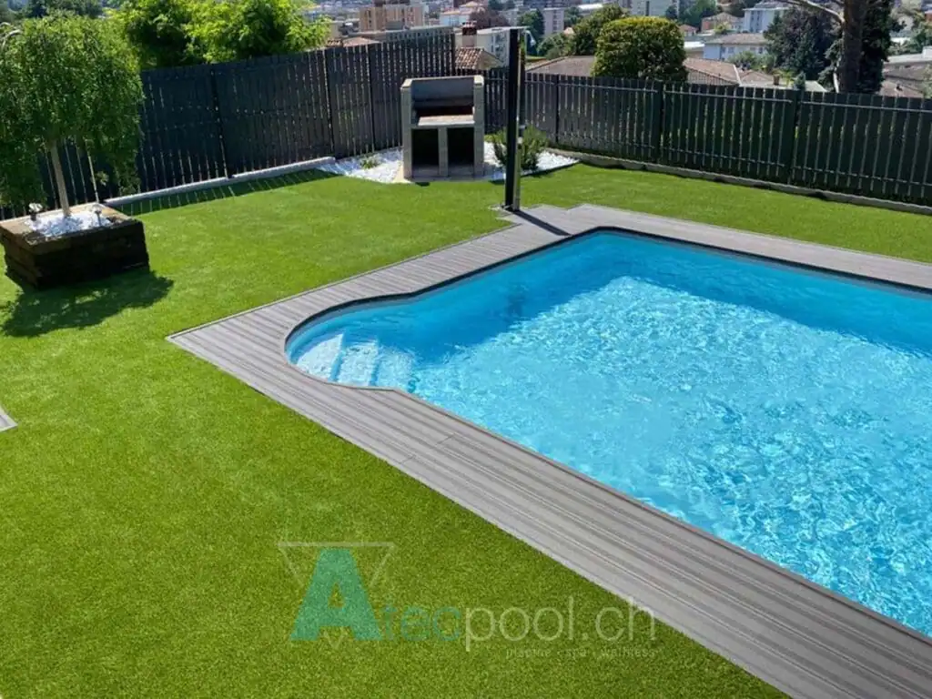 Piscina interrata con bordo sfioro, acqua cristallina, giardino ben curato e vista sulla città.
