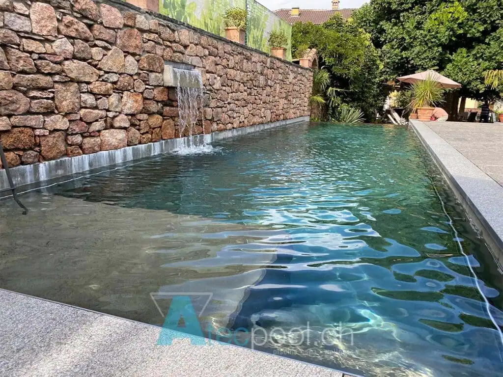 Acqua di piscina interrata con cascade in pietra, ambiente rinfrescante e rilassante.