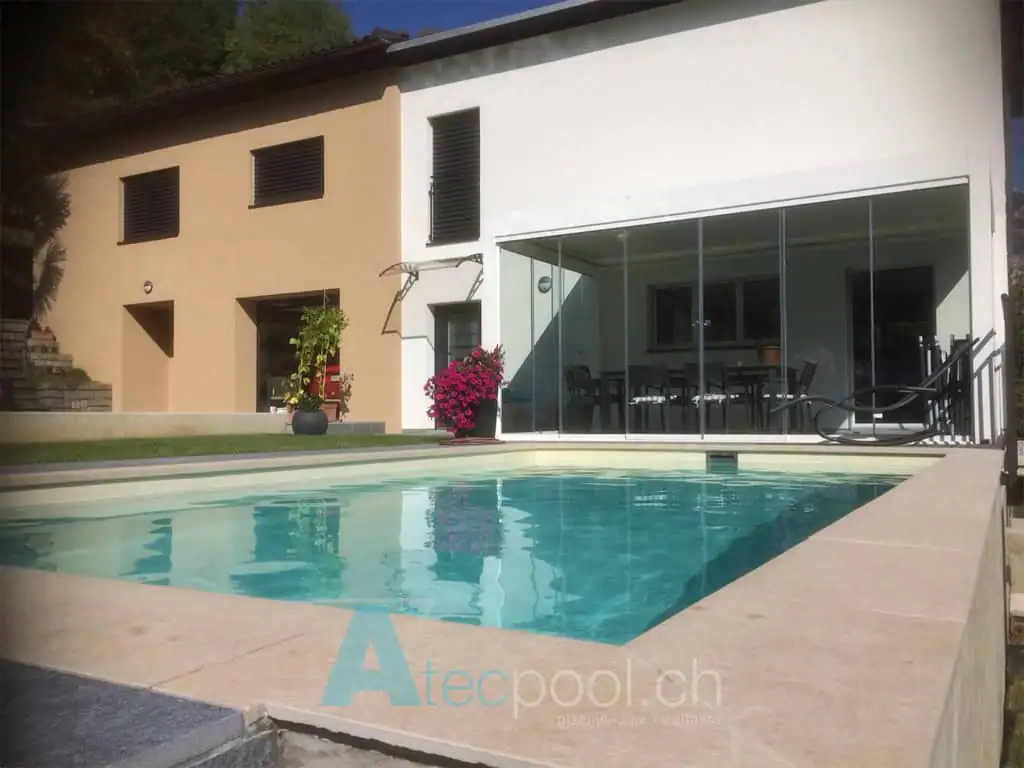 Ampio piscina interrata con bordo a sfioro sotto la terrazza moderna della casa. Facile accesso e spazio per il relax all'aperto, perfetta per il tempo libero e il benessere.
