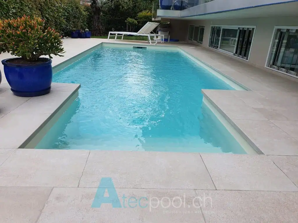 Piscina interrata con bordo a sfioro, acqua cristallina, ambiente moderno e tranquillo.