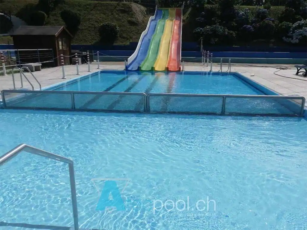 Acqua limpida in piscina interrata con scivolo colorato per bambini, ambiente di relax e divertimento.