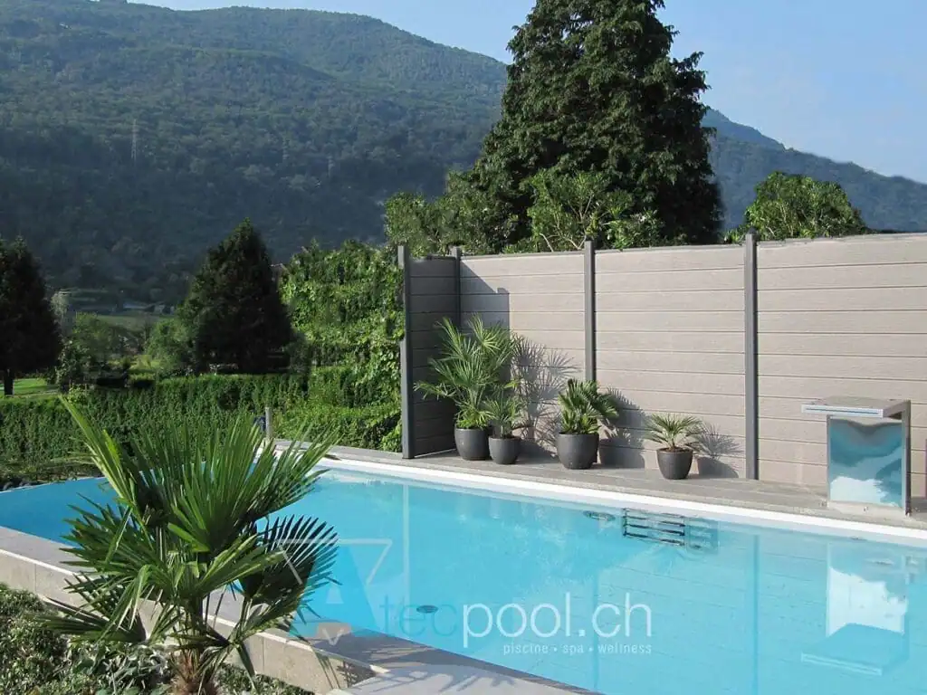 Piscina interrata con bordo a sfioro immersa in un ambiente naturale e verdeggiante.