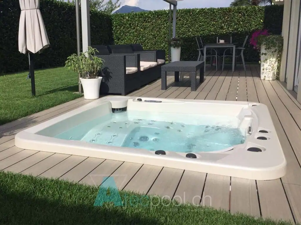Piscina a sfioro interrata con idromassaggio e area relax in giardino.