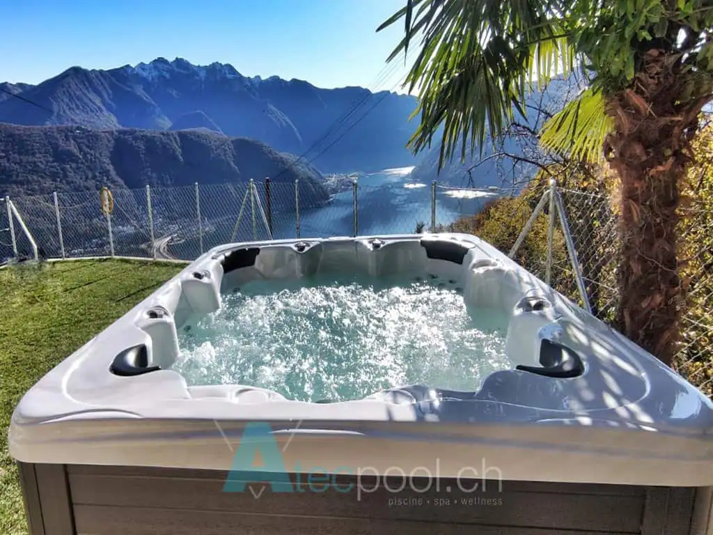 Jacuzzi all'aperto con vista sulle montagne e lago, ambientazione di relax e benessere, piscina spa idromassaggio.