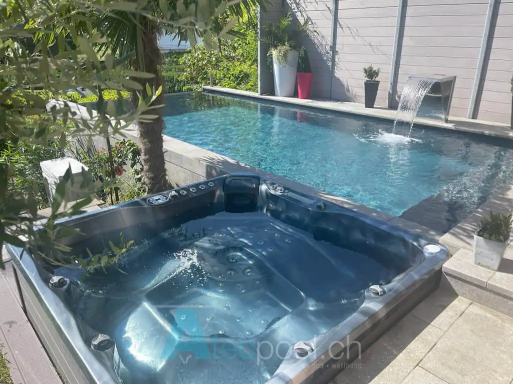 Piscina interrata con vasca idromassaggio Jacuzzi sul terrazzo all'aperto, circondata da piante e decorazioni colorate.