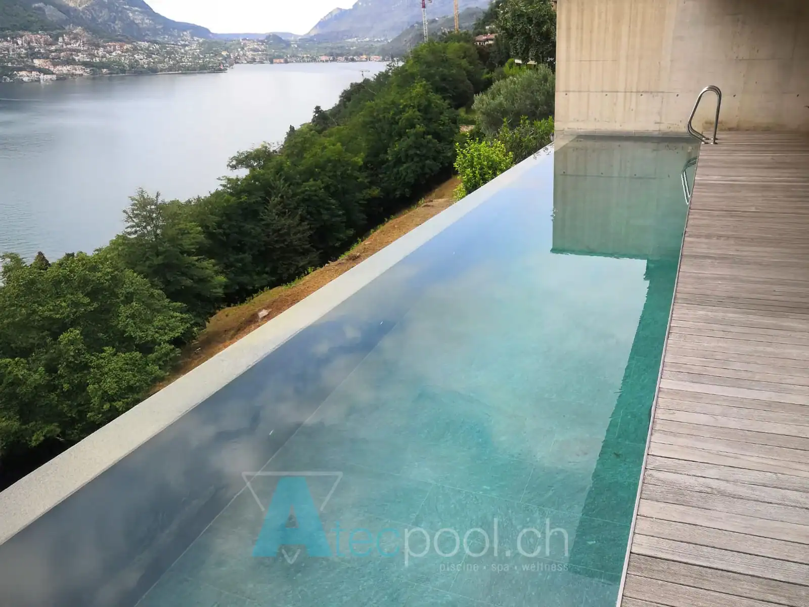 Piscina a sfioro con rivestimento in legno e vista panoramica sul lago