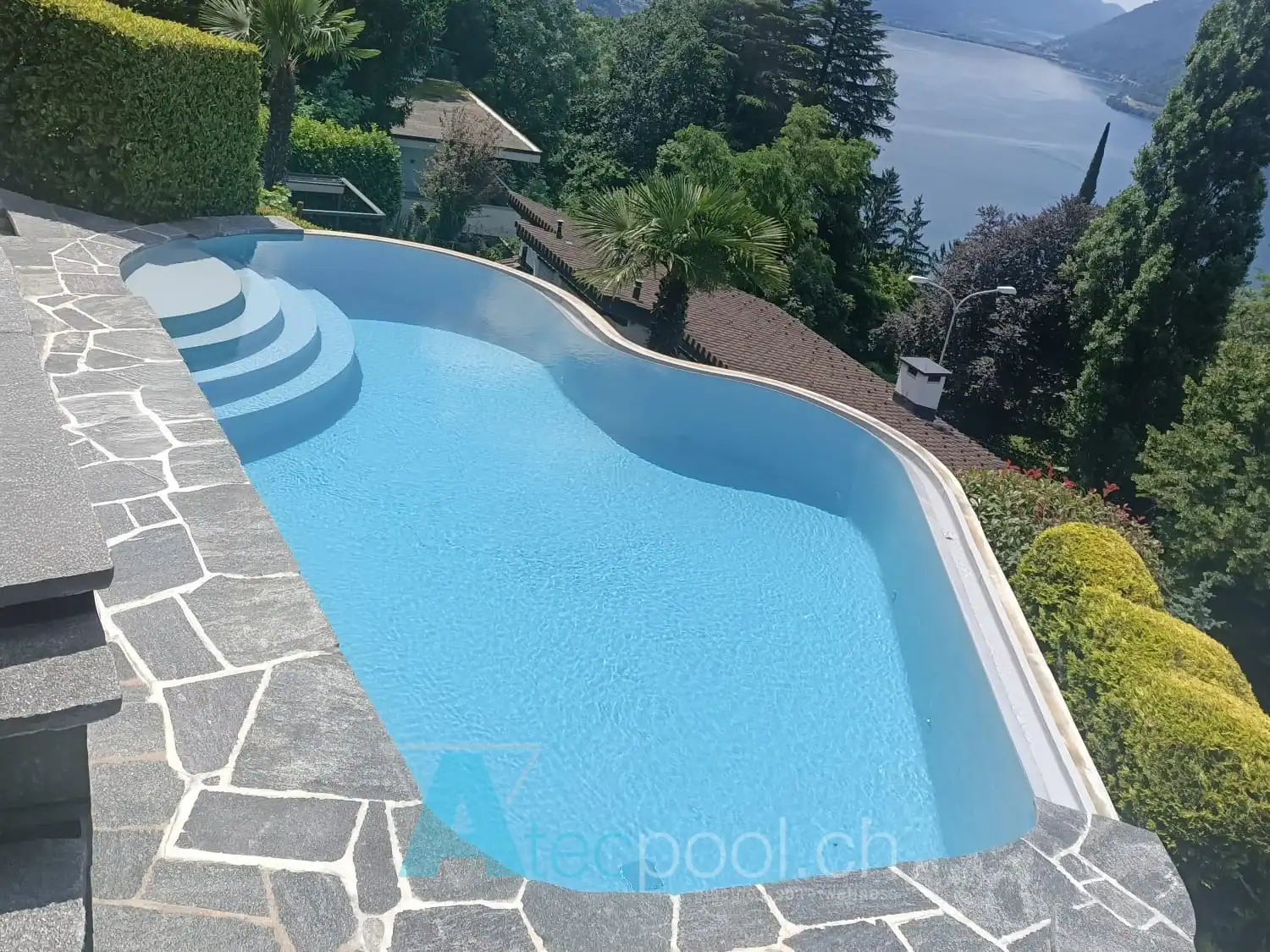 Piscina a forma libera con scala circolare e vista panoramica sul lago