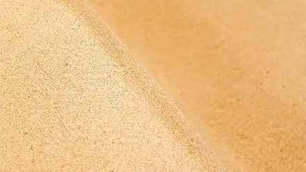 Superficie di sabbia dorata, perfetta per ambienti di spa e wellness all'aperto.