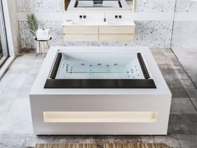 Vasca idromassaggio quadrata con rivestimento bianco, cuscini neri e illuminazione LED, in bagno elegante e luminoso