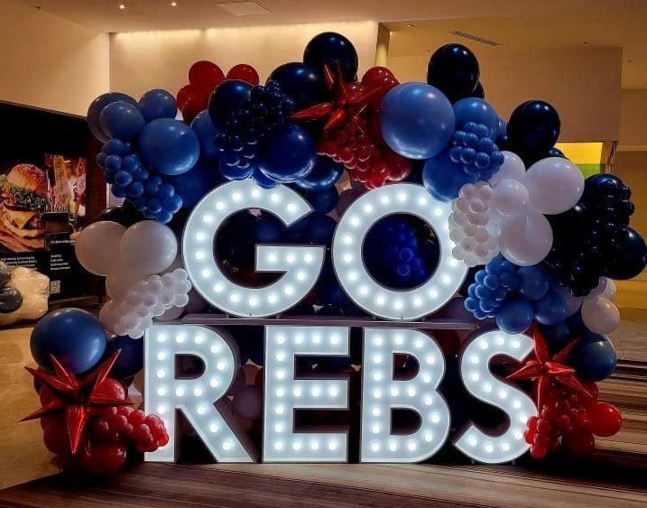 Balloon Decor Pricing Illuminated GO REBS for Ol' Miss rchampion reception at the Marriott Marquis, 4 ft marquee letters stacked , surrounded by custom balloon wall,colors red, white, and blue balloon decorations for a university celebration and school spirit event. Atlanta Balloon Designer created this custom event display featuring premium balloon décor designed for graduations, college University events, athletic celebrations, Grad event, proms, and campus activations. We provide balloon arches, balloon columns, custom backdrops, marquee letters, event rentals,balloon garlands, corporate décor, and professional event styling across Metro Atlanta.