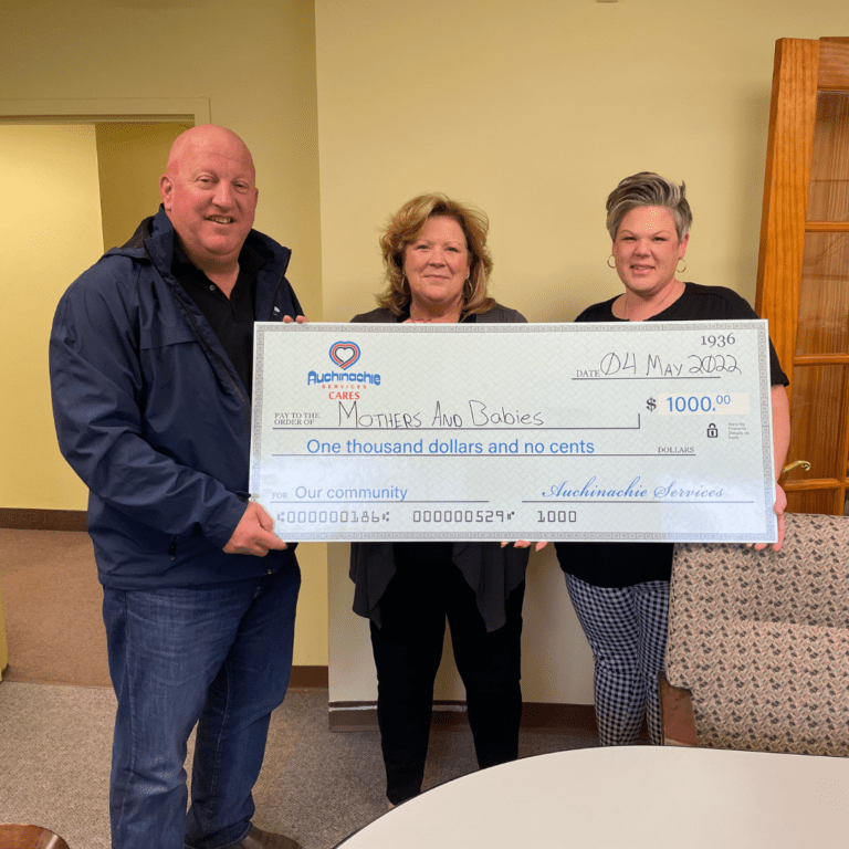 Three people proudly hold a $1000 check from Auchinachie Cares, made out to "Mothers and Babies" on May 4, 2023. It's a heartwarming moment that says as much about us as our commitment to the community.