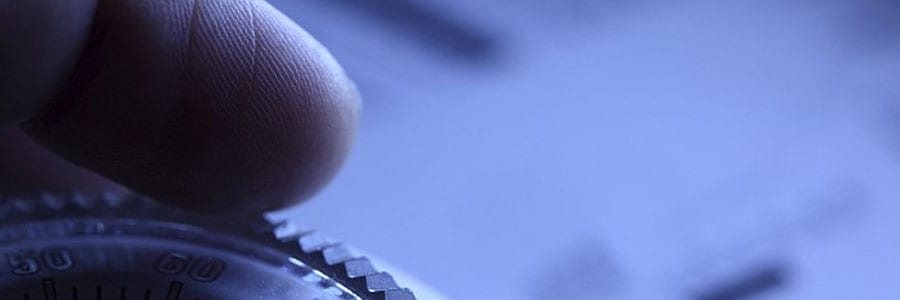 Close-up of a hand adjusting a dial on a device in a bluish light.