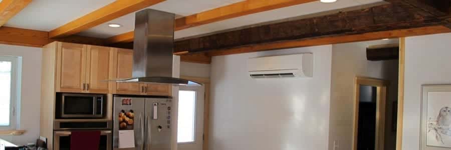 Modern kitchen with wooden beams, stainless steel appliances, a wall-mounted air conditioning unit, and recessed ceiling lights.