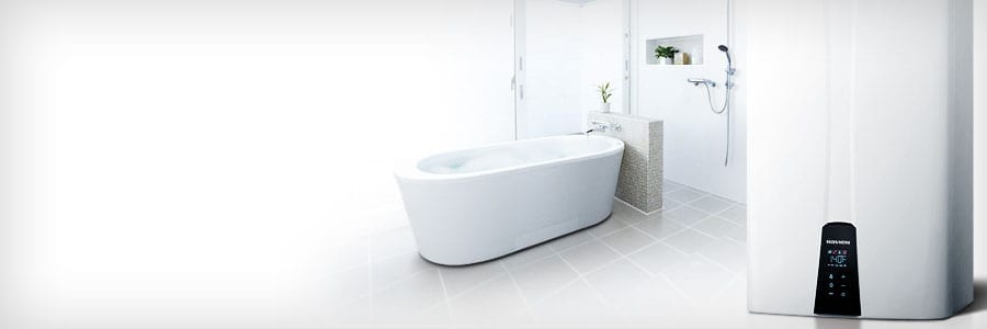 Minimalist bathroom with a white bathtub, tiled floor, and a wall-mounted shower. A digital water heater is visible in the foreground.