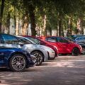 Reihe geparkter Autos in einem Park in Köln, umgeben von Bäumen.