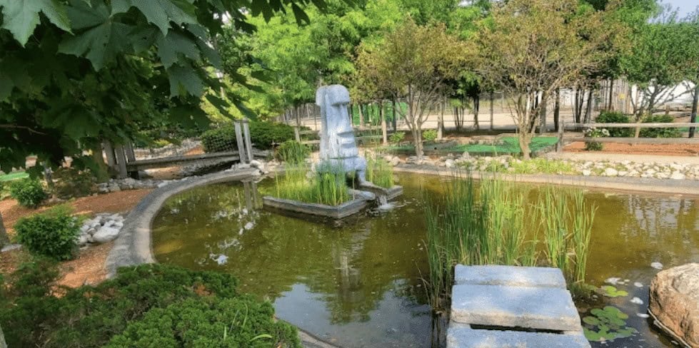 Fountain with a stone sculpture in a lush garden setting, symbolizing renewal and growth.