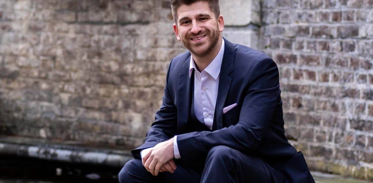 Eleganter Mann im Anzug vor Brückenmauer, professionelle Hochzeits- und Portraitfotografie.