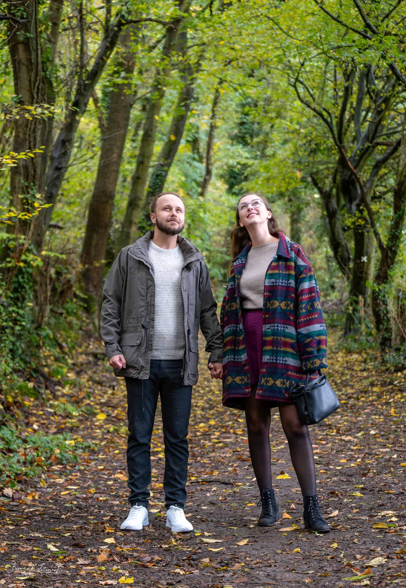 Zwei Menschen halten Händchen und erkunden den herbstlichen Wald in Aachen, perfekt für Hochzeits- oder Paarfotografie. Naturpaar bei Spaziergang im herbstlichen Wald in Aachen.