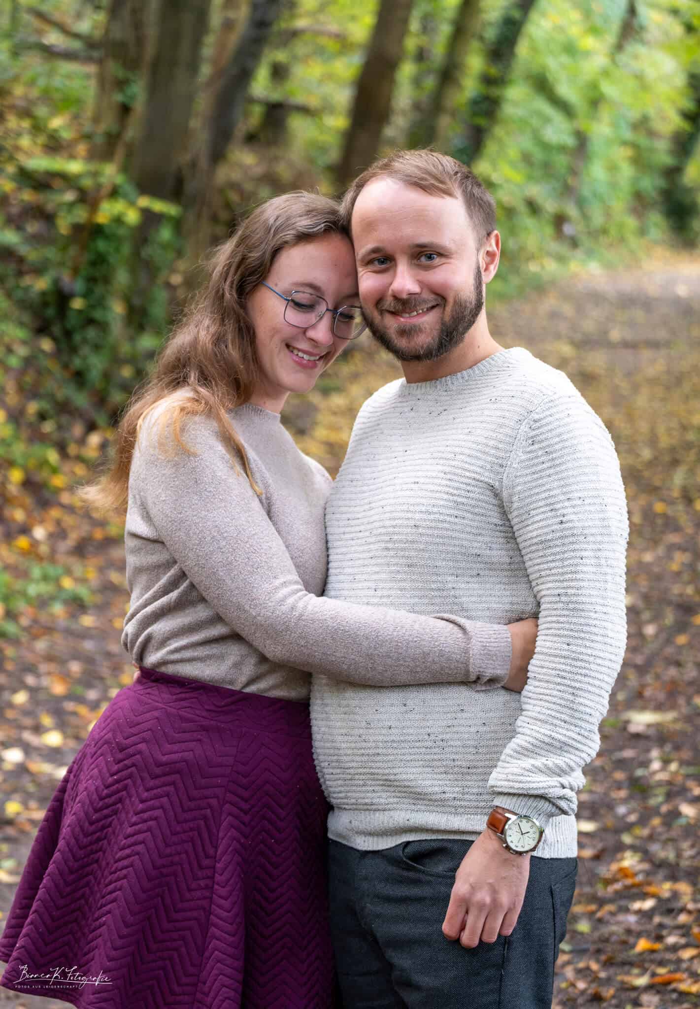 Liebespaar beim Fotoshooting im herbstlichen Wald in Aachen, liebevolle Stimmung festgehalten. Natürlich, hier sind die SEO-optimierten Texte für das Bild:.