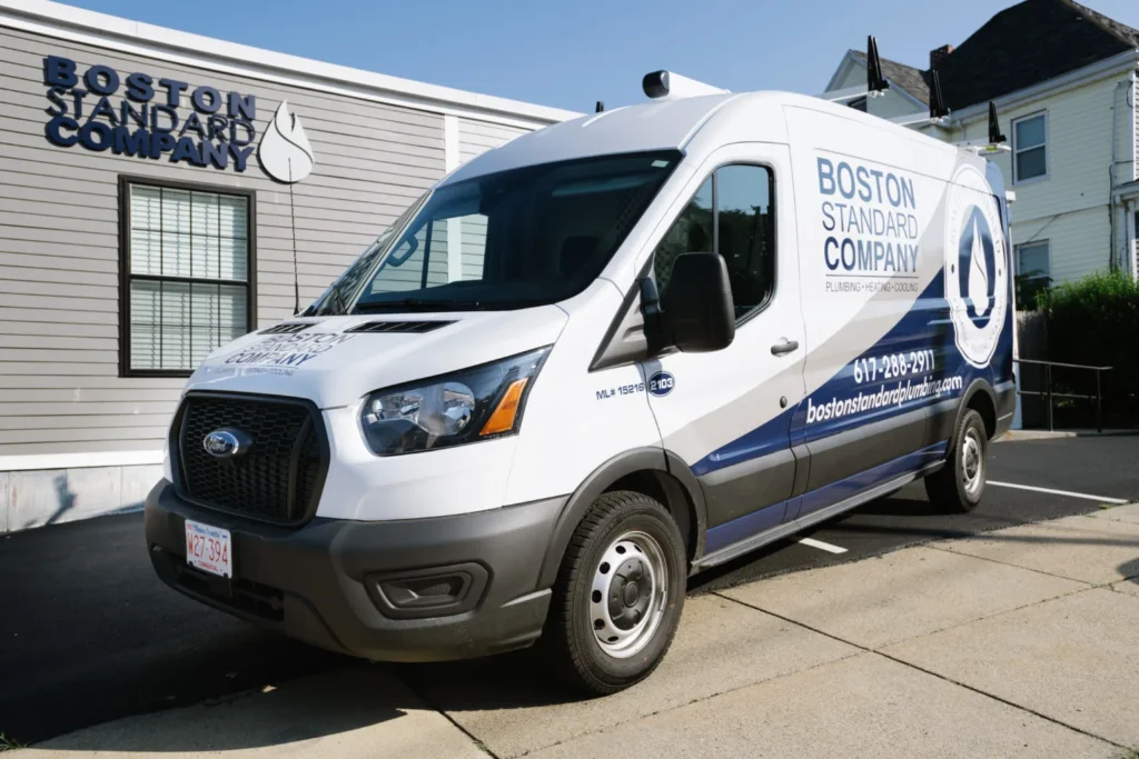 White Boston Standard Company van parked outside a building with the company logo on it.