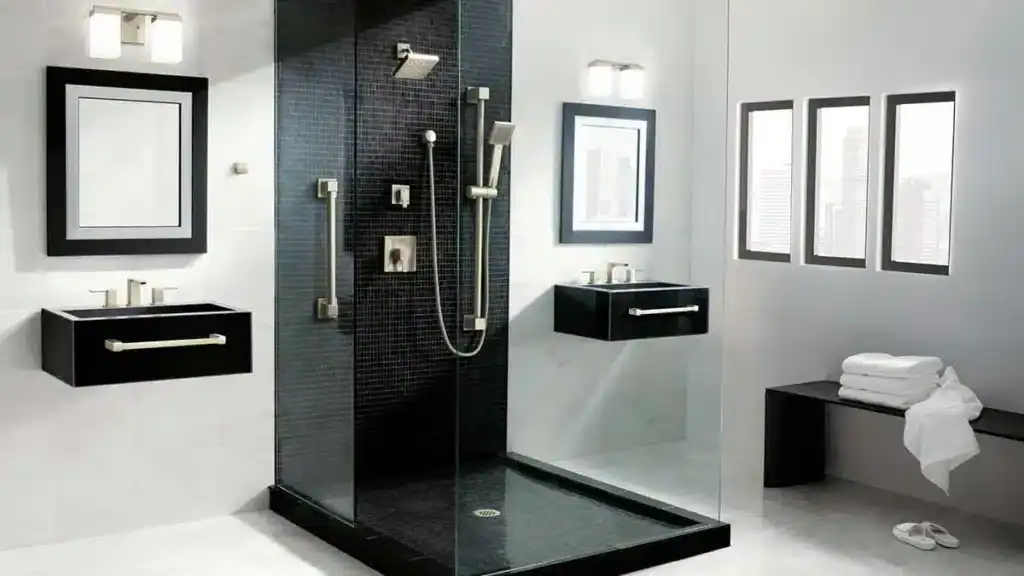 Modern bathroom with a glass-enclosed black-tiled shower, two wall-mounted sinks with mirrors, a bench with towels, and white slippers on the floor.