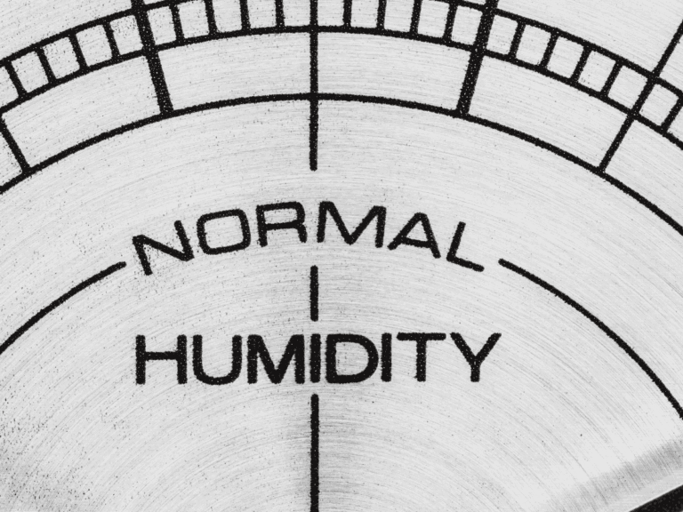Close-up of a humidity meter dial pointing to the "NORMAL HUMIDITY" range, with black text on a light metallic background.
