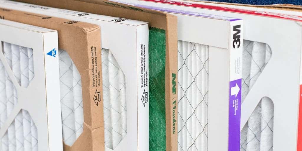 A close-up view of several boxed air filters of different brands and sizes standing vertically in a row.